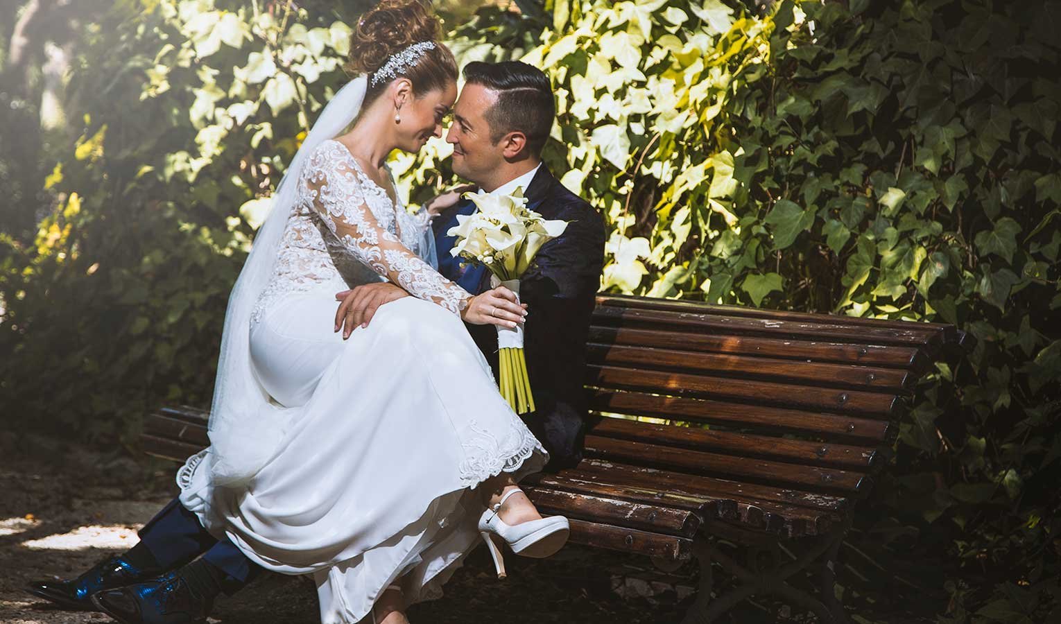 Novios sentados en un banco de madera rodeados de hiedra y naturaleza