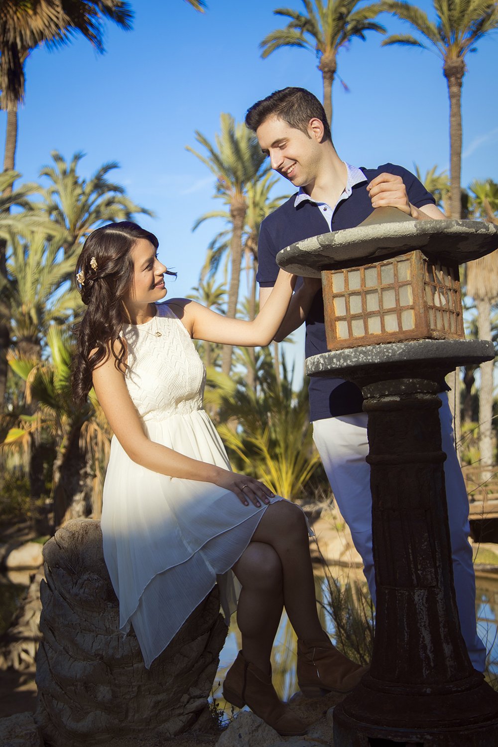Novios sonriendo con palmeras de fondo