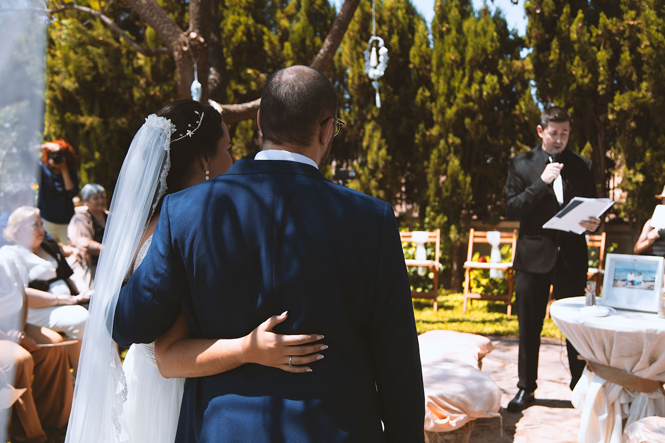 Vista trasera de los novios abrazándose emotivamente en el altar rodeados de la vegetación del jardín.