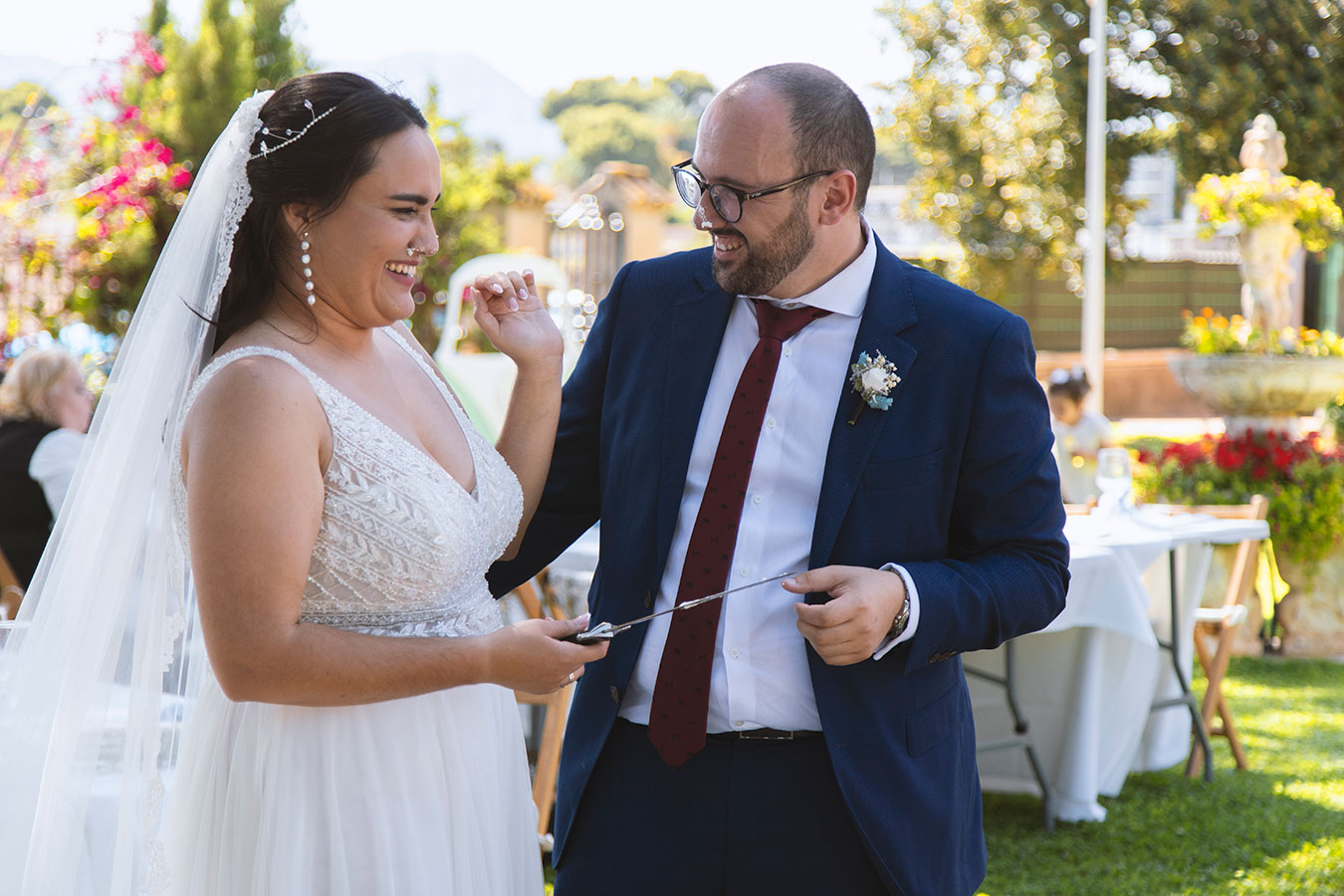 Pareja de novios sosteniendo juntos el cuchillo justo antes de cortar la tarta nupcial.