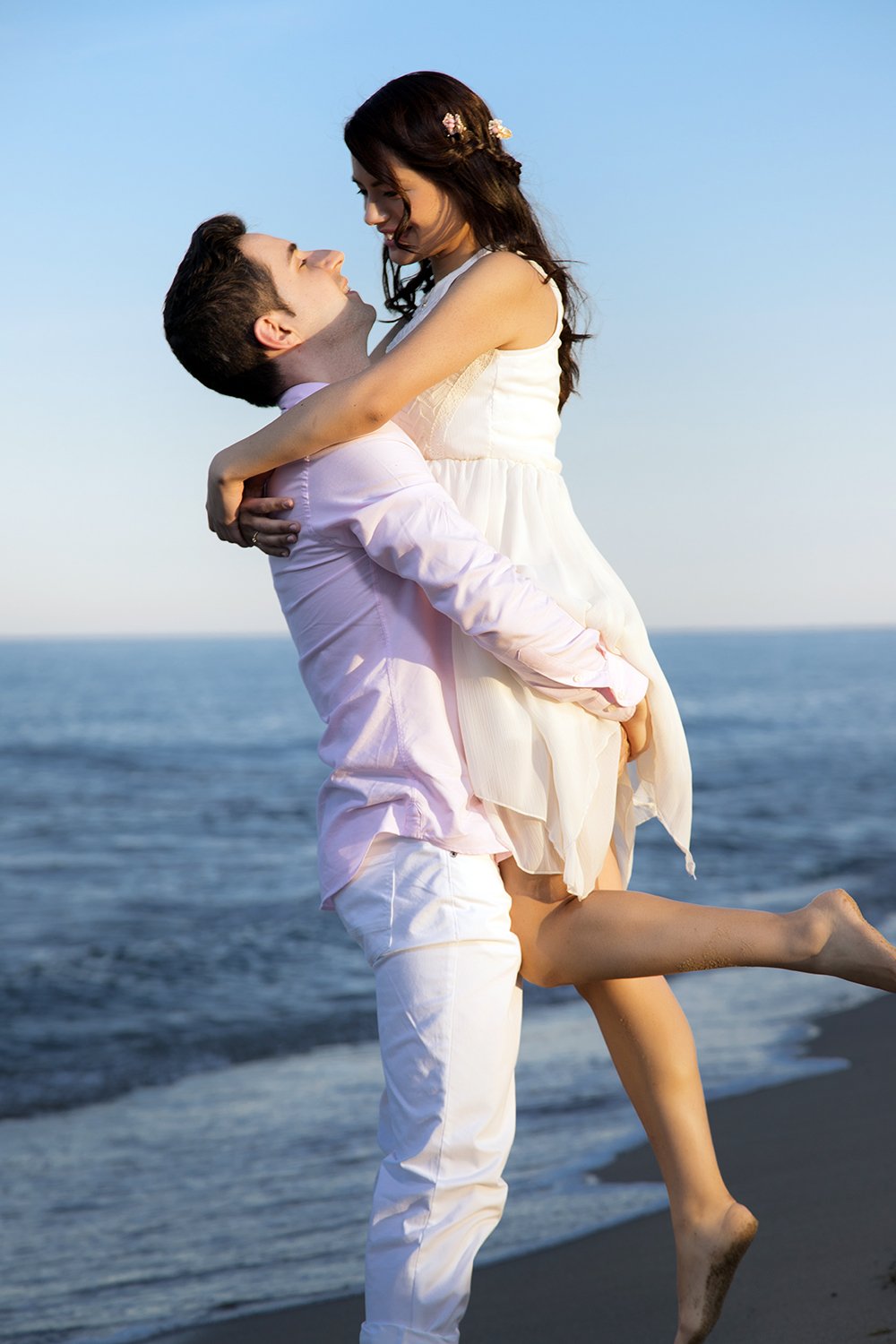 el novio levanta a la novia en brazos en la playa
