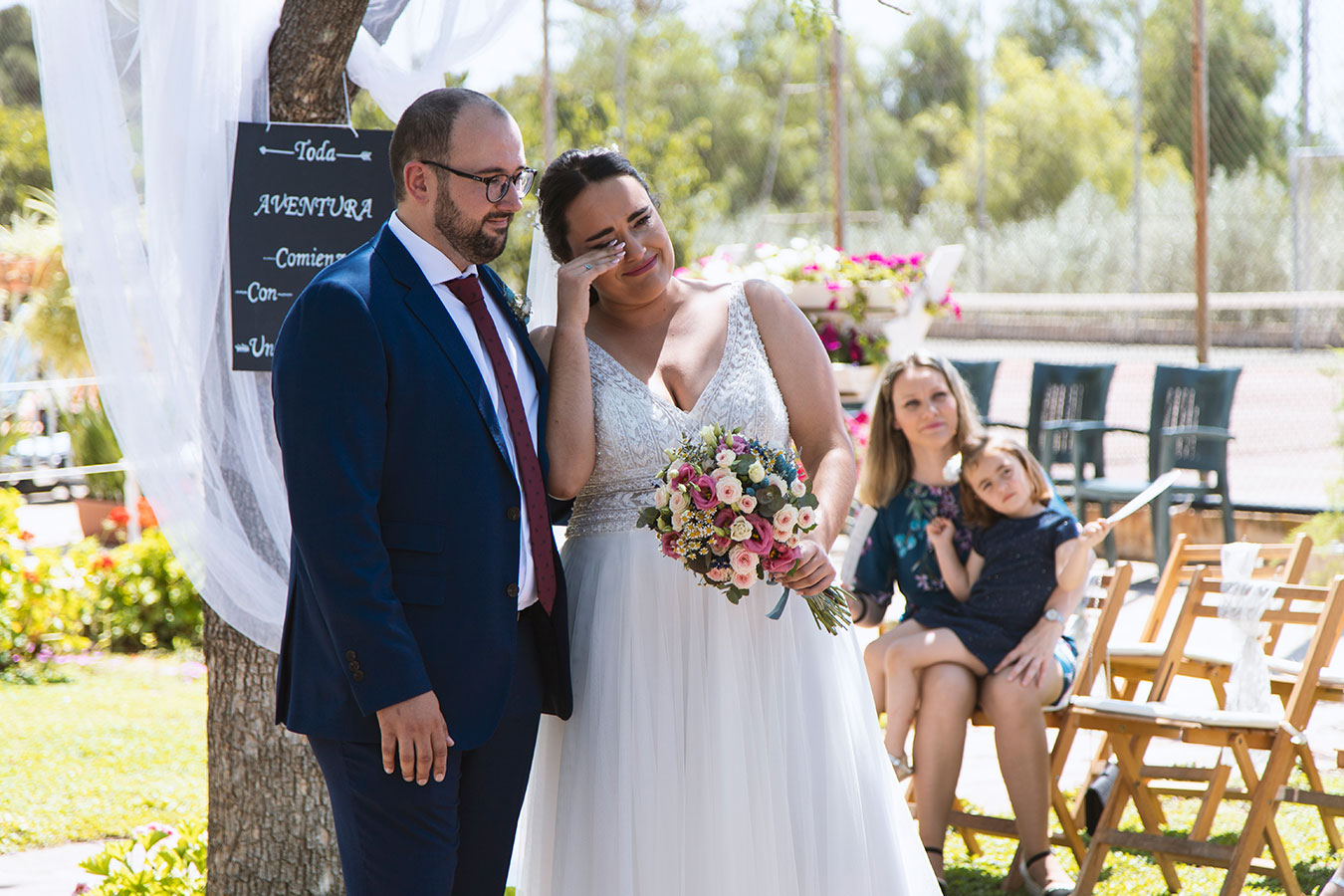 Fotografía documental de la novia secándose con delicadeza una lágrima de emoción durante el intercambio de votos.