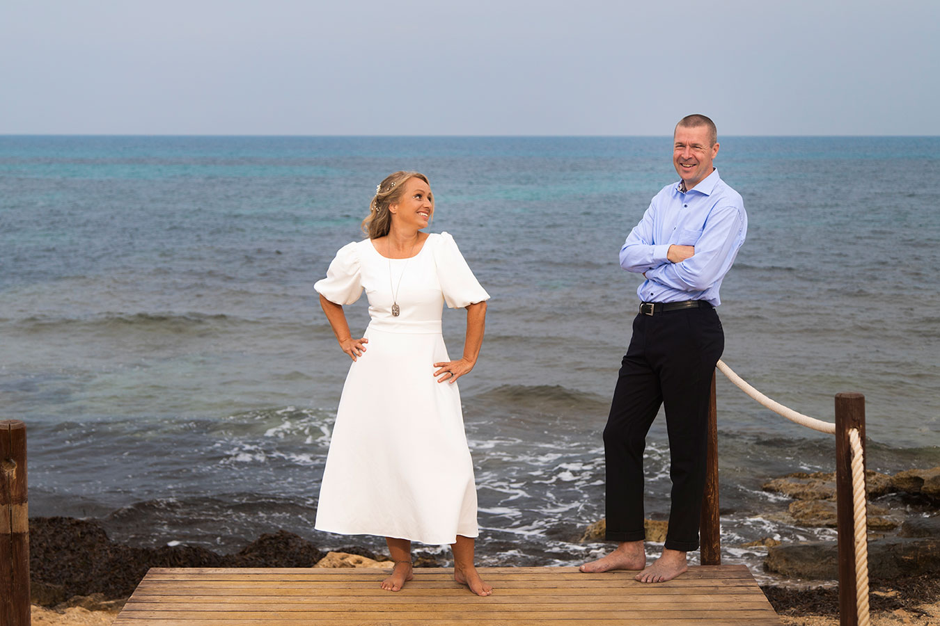Pareja de novios posando en la pasarela de madera de acceso a la playa en Cala Ferris, Torrevieja.