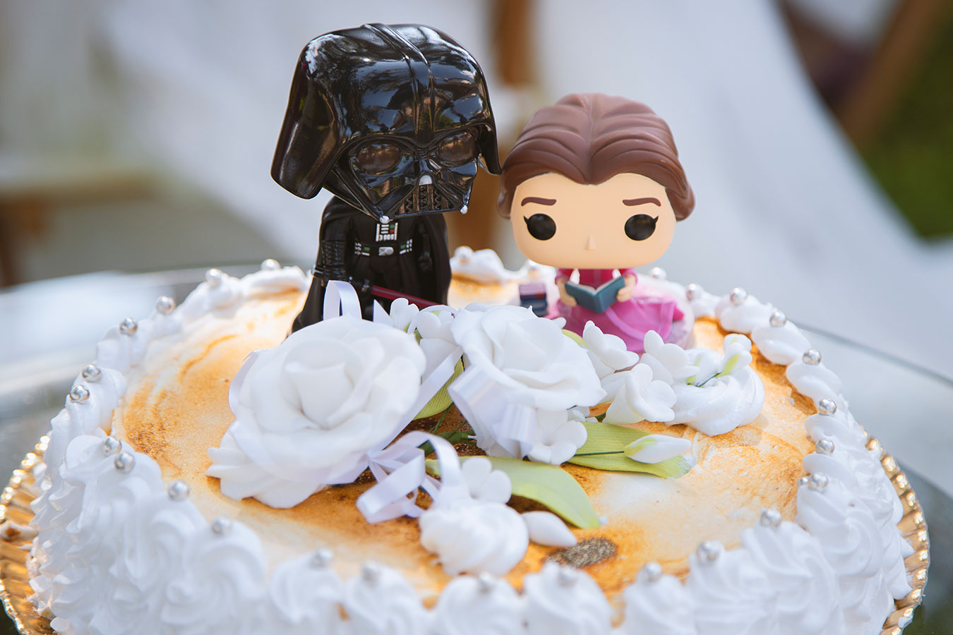 Detalle de la tarta nupcial coronada con dos figuras estilo Funko Pop personalizadas vestidas de novios.